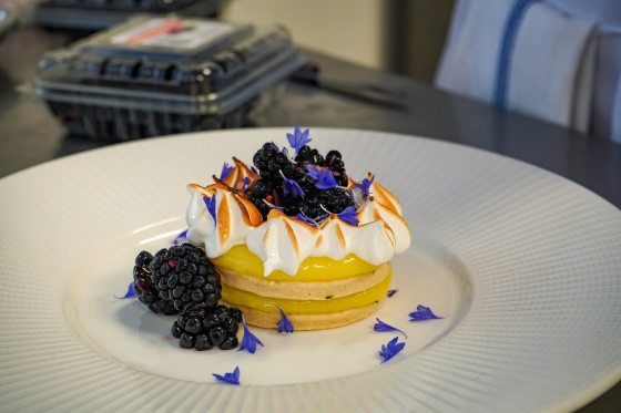 a lemon curd and meringue tart sitting on a white plate 